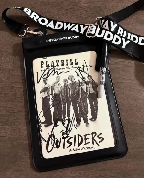 A signed Playbill for "The Outsiders: A New Musical" is elegantly displayed alongside The Broadway Buddy lanyard and a Sharpie pen in the Stagedoor Marker Holder.